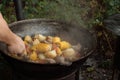 Large pieces of meat, ears of corn, potatoes and vegetables are fried in a cast-iron cauldron on an outdoor wood-burning stove. Royalty Free Stock Photo