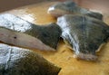 Large pieces of raw flounder close-up on a wooden board. The fish is peeled, cut and cooked for frying. Cooking fish dishes Royalty Free Stock Photo