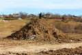 Large pile of dry soil mixed with rocks and construction material at local construction site in front of small hill Royalty Free Stock Photo