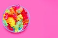 A large pile of multi-colored jelly marmalade candies in a glass bowl on a pink background Royalty Free Stock Photo