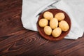 A large pile of raw and young potatoes in a light fabric on the dark brown wooden table. Fresh potatoes in a small brown basket. Royalty Free Stock Photo