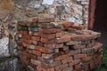 a large pile of red-orange bricks against the background of a broken old wall on the street. for introductory instructions books Royalty Free Stock Photo