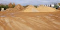 A large piles of construction sand with traces of tractor wheels