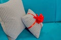 Pillows with bright red bow with patterned beige and brown upholstery lying on light blue fabric upholstery of sofa. Royalty Free Stock Photo