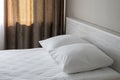 Large pillows lie on the double bed, white bed linen, dark curtains on the Windows, close-up. Royalty Free Stock Photo