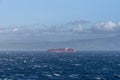 Large, pink container cargo ship sailing near Spanish sea coast.