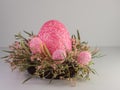 Large pink Easter egg and 3 smaller pink Easter eggs sitting on a pink and green wreath on a white background. Spring holiday