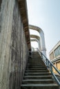 Large pipes reach over the exterior stairway of a concrete building