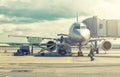 Large plane at airport during pushback with ground crew person istanding on vehicle. Tonned Royalty Free Stock Photo