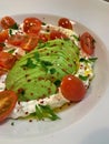 Large plate of creamy cheese with olive oil, sliced ripe avocado, tomatoes cut in half, healthy food, fresh vegetables and dairy p