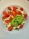 Large plate of creamy cheese with olive oil, sliced ripe avocado, tomatoes cut in half, healthy food, fresh vegetables and dairy p