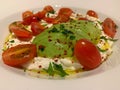 Large plate of creamy cheese with olive oil, sliced ripe avocado, tomatoes cut in half, healthy food, fresh vegetables and dairy p