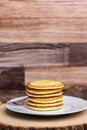 A large plate stack of pancakes with a fork against a wood background.