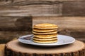 A large plate stack of pancakes with a fork against a wood background plain with no syrup