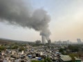 A large plume of smoke rising from a fire in a slum in the suburb of Malad.