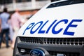 Large police sign on the front of a white patrol vehicle.