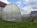 A large polycarbonate greenhouse is installed on the garden plot