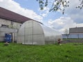 A large polycarbonate greenhouse is installed on the garden plot