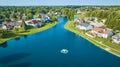 Large pond with water fountain aerial over neighborhood with large expensive houses