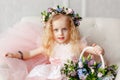 Large portrait of a cute little girl in a wreath of flowers and a beautiful bouquet of flowers in a bright studio Royalty Free Stock Photo