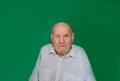 a large portrait of an old man with a serious look on an isolated green background.