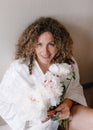 a large portrait of a woman with curly hair holding a bouquet of white peonies in her hand.