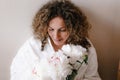 a large portrait of a woman with curly hair holding a bouquet of white peonies in her hand.