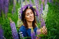 A large portrait of a woman in a wreath on a lupine field with her eyes closed. A meadow of purple flowers in summer. A girl with Royalty Free Stock Photo