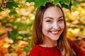 A large portrait of a young beautiful woman in a red sweater against the background of fallen yellow maple leaves. Autumn in the Royalty Free Stock Photo