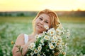 A large portrait of a young, plump, beautiful woman resting on a chamomile field at sunset. A plus-size woman in a white sundress Royalty Free Stock Photo