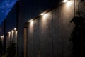 Large pot lights illuminating a concrete wall with bricks at twilight