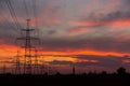 Large power poles for transporting electricity and a beautiful, orange, dramatic sunset Royalty Free Stock Photo