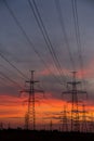 Large power poles for transporting electricity and a beautiful, orange, dramatic sunset Royalty Free Stock Photo