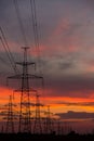 Large power poles for transporting electricity and a beautiful, orange, dramatic sunset Royalty Free Stock Photo