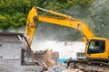 Large powerful yellow excavator destroys an old industrial building