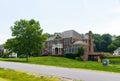Large private brick country house with a green trimmed lawn. Sunny summer day and blue sky
