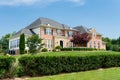 Large private country house with a green trimmed lawn. Sunny summer day and blue sky