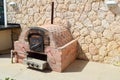 Professional industrial brown stone oven grill oven with a tube for cooking frying food from a stone tiled on a stone wall