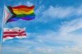 large progress lgbtq flag and flag of the District of Columbia state, USA waving in the wind at cloudy sky. Freedom and love