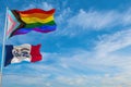 large progress lgbtq flag and flag of Iowa state, USA waving in the wind at cloudy sky. Freedom and love concept. Pride month.