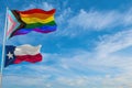 large progress lgbtq flag and flag of Texas state, USA waving in the wind at cloudy sky. Freedom and love concept. Pride month.