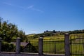 Large property with house and fence in the foreground and large garden on a hill in the background