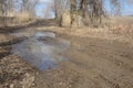 Large puddle on dirt road in early spring. Obstacle for car. Transport tire tracks Royalty Free Stock Photo