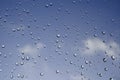 Large rain drops on the window glass with dark blue sky and clouds. Selective focus Royalty Free Stock Photo