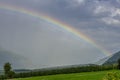 A large rainbow emerges from the clouds over an apple planted field in Val Venosta, Prato allo Stelvio, Italy Royalty Free Stock Photo