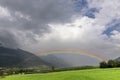 A large rainbow emerges from the clouds over an apple planted field in Val Venosta, Prato allo Stelvio, Italy Royalty Free Stock Photo