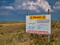 A large rectangular sign on the North Norfolk Coast Path warns the public that the coast is subject to tidal changes Royalty Free Stock Photo