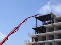 Large red articulated crane working on a large modern housing development site with concrete framework and safety barriers Royalty Free Stock Photo