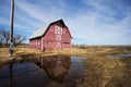 Large red barn reflected in puddle of water