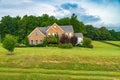 Large Red Brick Traditional Colonial Home House on a large Wooded lot. Green lawn and blue sky